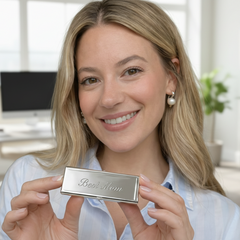 Woman holding a silver pillbox with best mom engraved in front of a neutral background