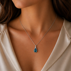 Close-up of a woman wearing a crystal necklace with a blue pendant.