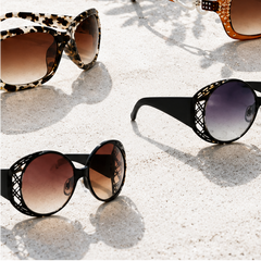 Four pairs of crystal sunglasses on a white surface with a scenic background