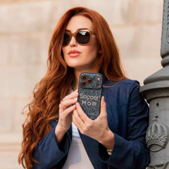 Woman holding a crystal iphone case with 'Soccer Mom' text against a stone wall background