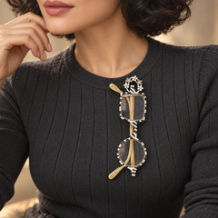 Silver-tone floral crystal eyeglasses holder pin worn on a charcoal sweater holding reading glasses; glasses not included